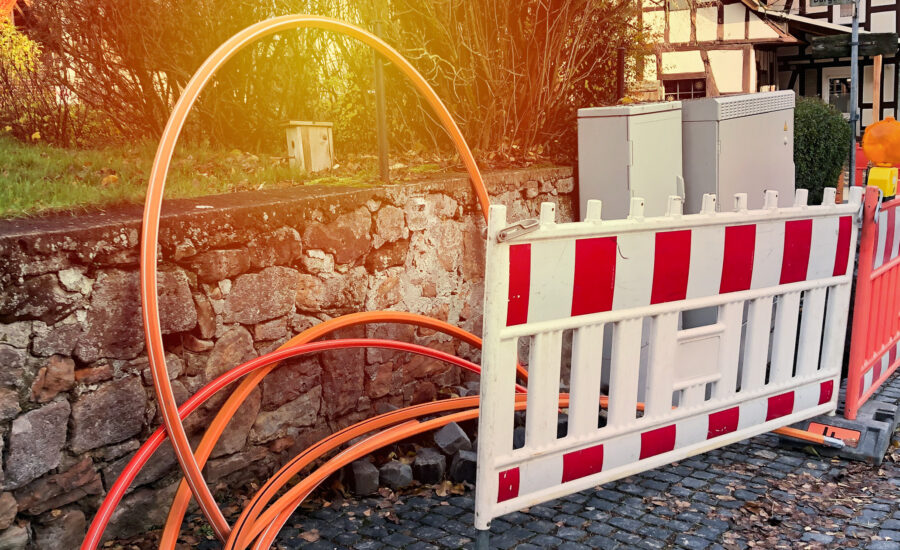 Baustellen-Barken und Glasfaser-Kabeln auf Dorf-Gehweg