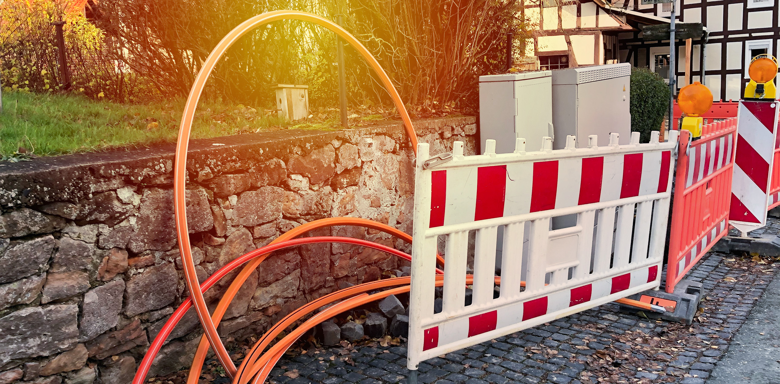 Baustellen-Barken und Glasfaser-Kabeln auf Dorf-Gehweg